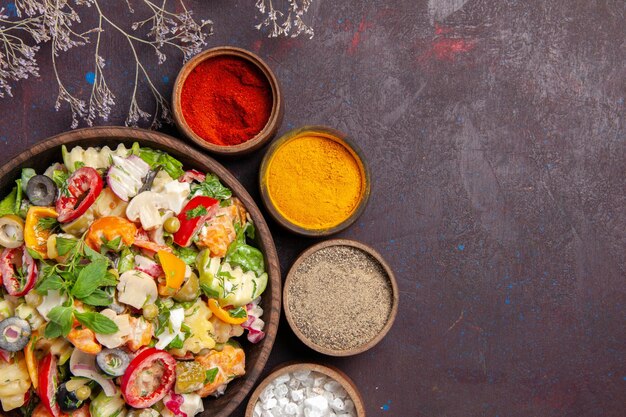 Draufsicht auf frisches Gemüse. Salat mit verschiedenen Gewürzen auf Schwarz