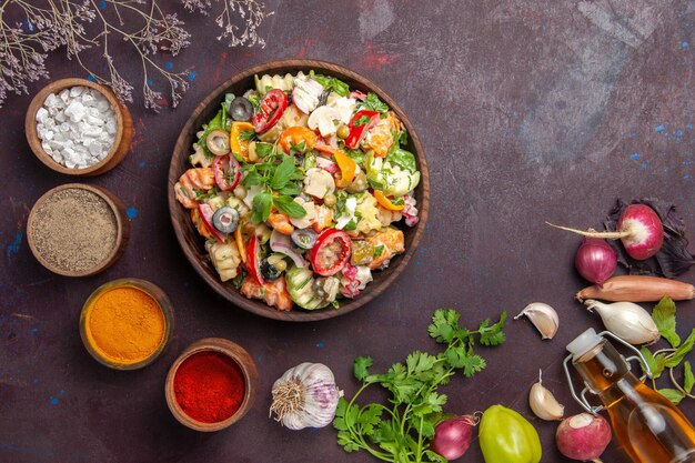 Draufsicht auf frisches Gemüse. Salat mit verschiedenen Gewürzen auf schwarzem Tisch