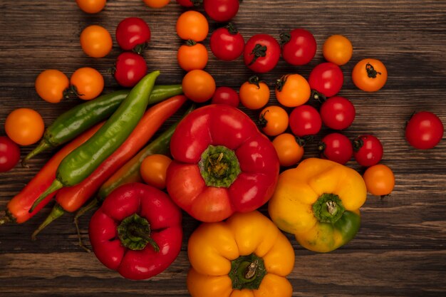 Draufsicht auf frisches Gemüse wie weiche Tomaten und Paprika isoliert auf einer Holzwand