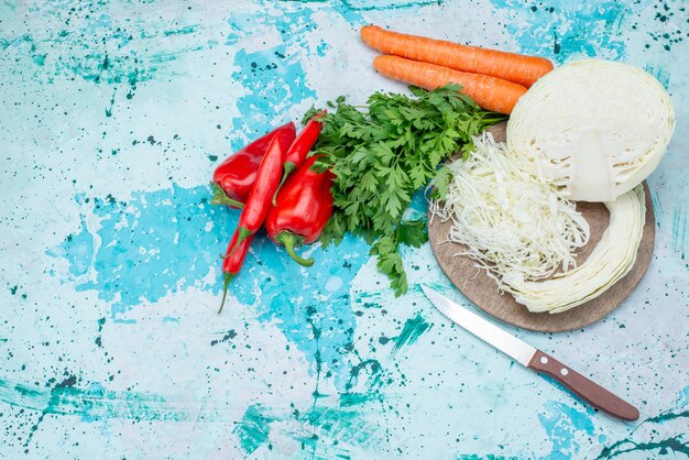 Draufsicht auf frisches Gemüsegrün geschnittene Kohlkarotten und Paprika auf hellblauem Schreibtisch, Lebensmittelmahlzeitgemüsemittagessen gesunder Salat