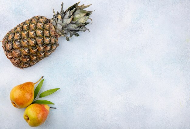 Draufsicht auf Früchte als Ananas und Pfirsiche auf weißer Oberfläche