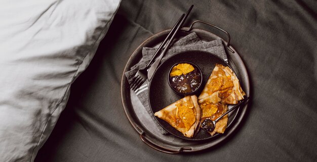 Draufsicht auf Frühstücks-Crepes mit Marmelade auf dem Bett