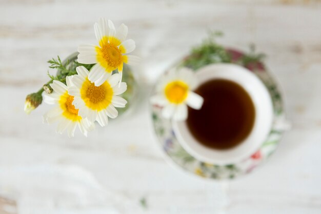 Draufsicht auf Gänseblümchen mit unscharfen Tasse Tee