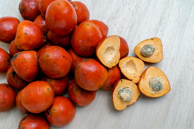 Draufsicht auf ganze und halbierte Chontaduro-Früchte auf dem Holztisch