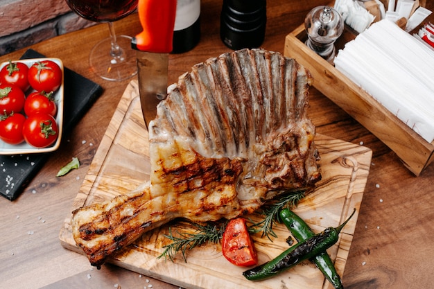 Draufsicht auf gegrillte Rippen, die mit Gemüse auf einem Holzbrett serviert werden