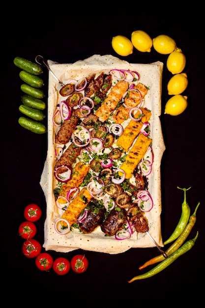 Draufsicht auf gemischten Kebab, der mit frischem Gemüse auf Schwarz serviert wird