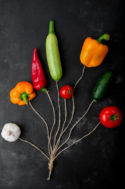 Draufsicht auf Gemüse als Knoblauch, Pfeffer, Zucchini, Tomate und Gurke auf schwarzer Oberfläche