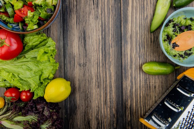 Draufsicht auf Gemüse als Tomaten-Salat-Basilikum mit Zitronengemüsesalaten und Reibe auf Holzoberfläche mit Kopierraum