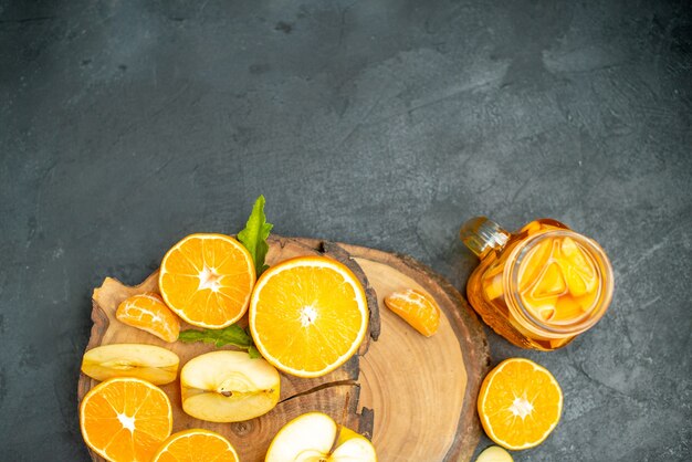 Draufsicht auf geschnittene Äpfel und Orangen auf Holzbrettcocktail auf dunklem Hintergrund