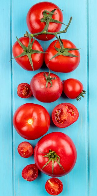 Draufsicht auf geschnittene und ganze Tomaten auf blauer Oberfläche