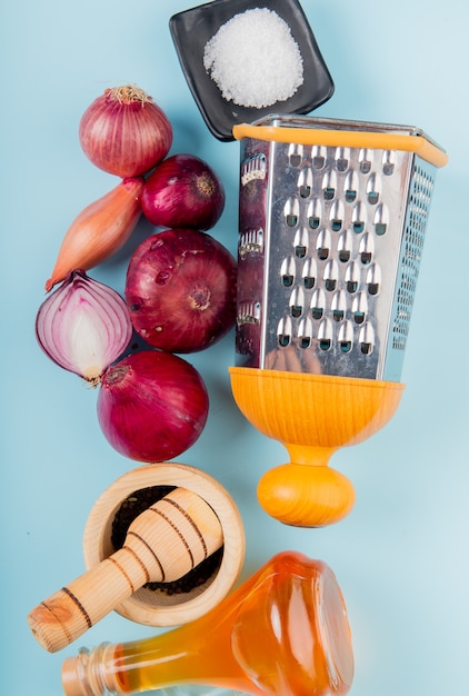 Kostenloses Foto draufsicht auf geschnittene und ganze zwiebeln mit geschmolzener butter, schwarzem pfeffer, salz und reibe auf blau