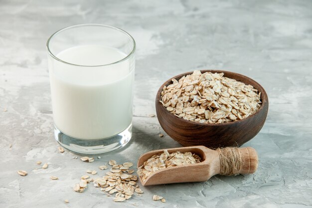 Draufsicht auf Glasbecher gefüllt mit Milch und Hafer innerhalb und außerhalb des braunen Topfes auf weißem Hintergrund