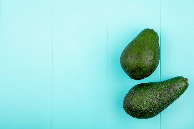 Draufsicht auf grüne und frische Avocados auf blauer Oberfläche