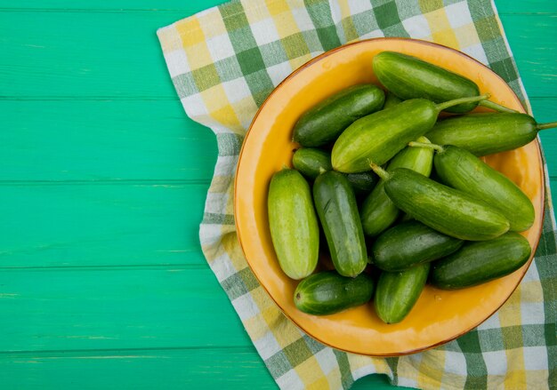 Draufsicht auf Gurken in Platte auf Stoff und grüner Oberfläche mit Kopierraum