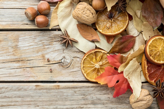 Draufsicht auf Herbstblätter mit Kastanien und getrockneten Zitrusfrüchten
