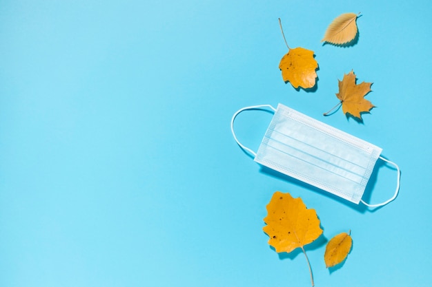 Draufsicht auf Herbstblätter mit medizinischer Maske und Kopienraum