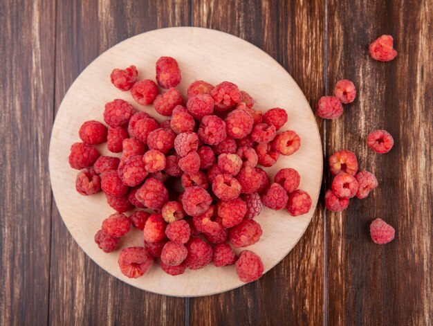 Draufsicht auf Himbeeren auf Schneidebrett und auf Holzoberfläche