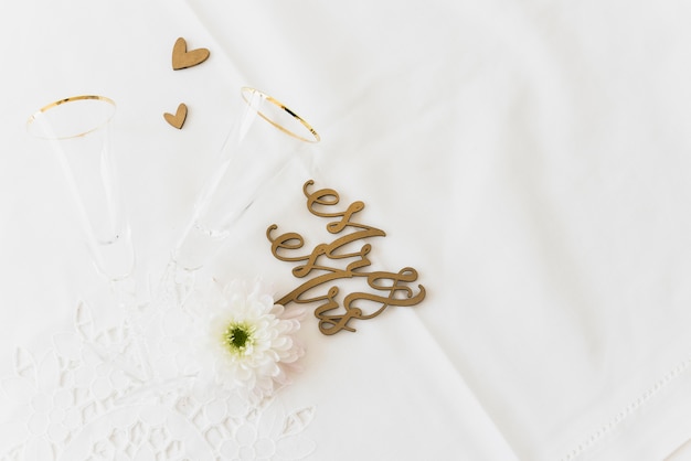 Draufsicht auf Hochzeitswort Herr und Frau mit Blume; Trinkglas und Herzform auf weißer Oberfläche
