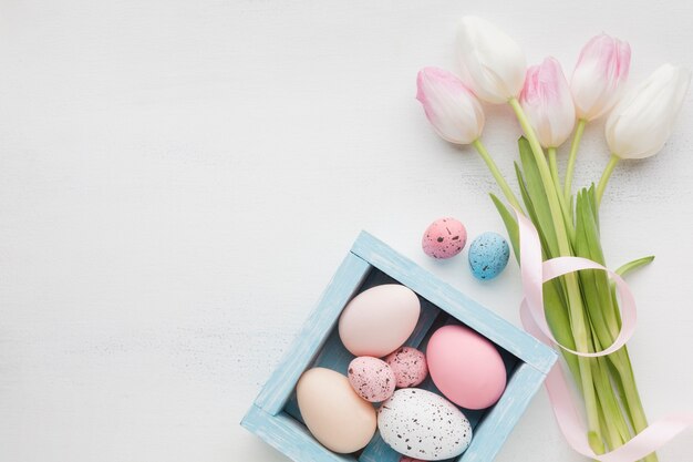 Draufsicht auf hübsche Tulpen mit bunten Ostereiern