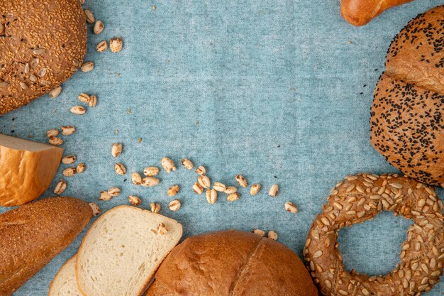 Draufsicht auf Hühneraugen und verschiedene Arten von Brot als weißer Bagel-Baguette-Kolben auf blauem Hintergrund mit Kopienraum