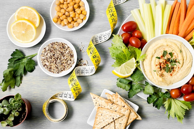 Kostenloses Foto draufsicht auf hummus mit gemüsesortiment und maßband