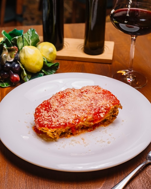 Draufsicht auf italienische Lasagne, garniert mit Tomatensauce und geriebenem Parmesan