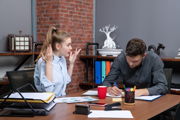 Draufsicht auf junge hart arbeitende, fokussierte Managementmitarbeiter, die ein Thema in der Büroumgebung diskutieren discuss