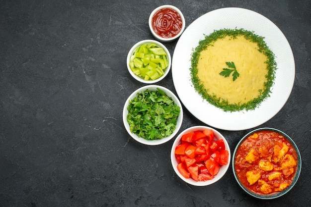 Draufsicht auf Kartoffelpüree mit Grüns und Tomaten auf Grau