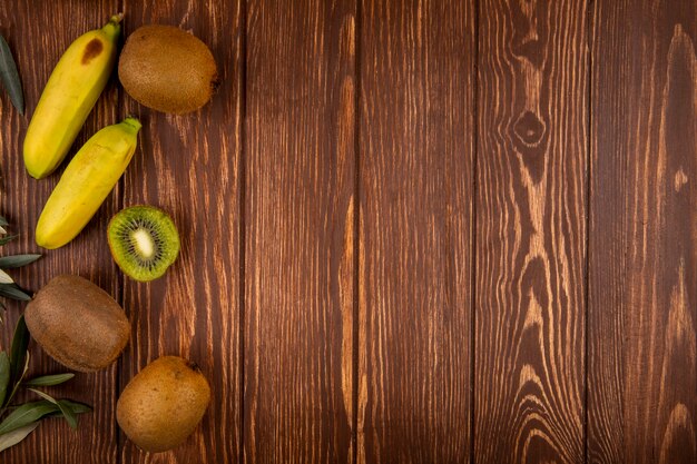 Draufsicht auf Kiwi- und Bananenfrüchte isoliert auf Holz mit Kopierraum