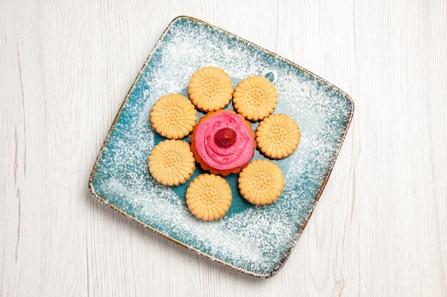 Draufsicht auf kleine süße Kekse mit Obstkuchen im Teller auf weißem Tisch white
