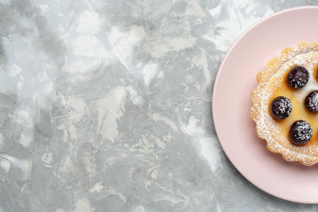 Draufsicht auf kleinen köstlichen Kuchen mit Kirschen innerhalb Platte auf Licht