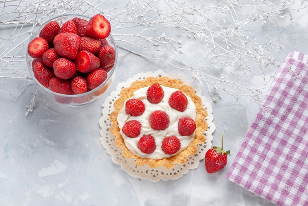 Draufsicht auf kleinen Kuchen mit Sahne und frischen roten Erdbeeren auf leichter Kuchenfrucht-Beeren-Kekscreme