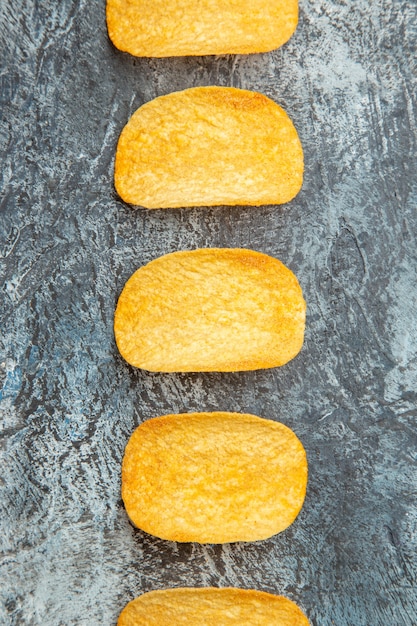 Kostenloses Foto draufsicht auf knusprig gebackene fünf chips, die in einer reihe auf grauem hintergrund aufgereiht sind