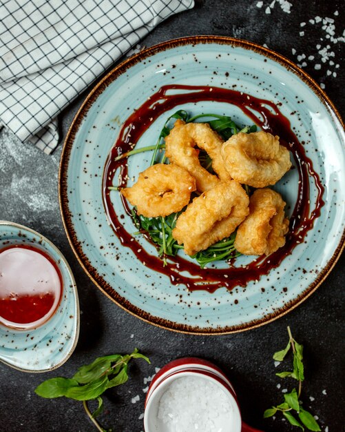 Draufsicht auf knusprig gebratene Calamari-Ringe, garniert mit Teriyaki-Sauce und Sesam