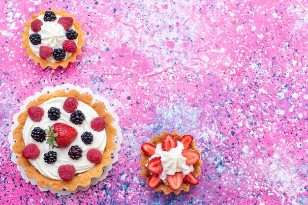 Draufsicht auf köstliche cremige Kuchen mit verschiedenen Beeren auf lila hellem Fruchtbeerenkuchen-Keksauflauf