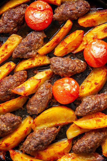 Draufsicht auf köstliche Fleischkoteletts gebacken mit Kartoffeln und Tomaten