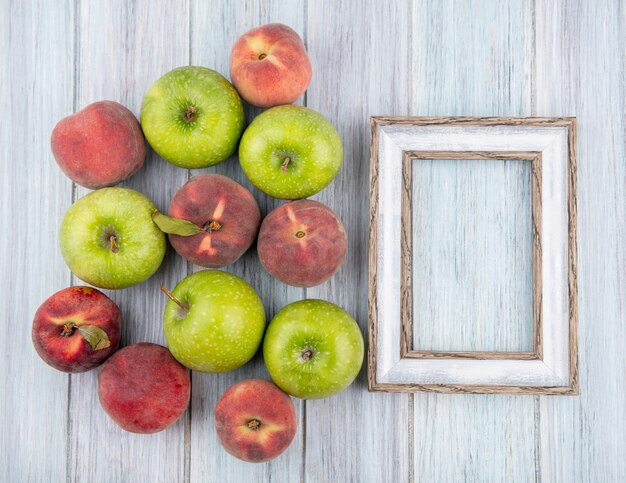 Draufsicht auf köstliche frische bunte Früchte wie Apfel und Pfirsiche auf grauem Holz mit Kopienraum