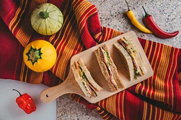 Draufsicht auf köstliche geschnittene Sandwiches mit Schinken, Käse, Kräutern und Gemüse auf dem Tisch