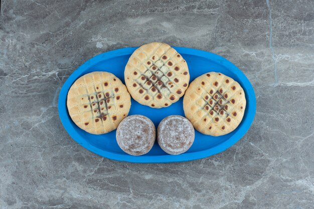 Draufsicht auf köstliche Kekse auf blauer Holzplatte.