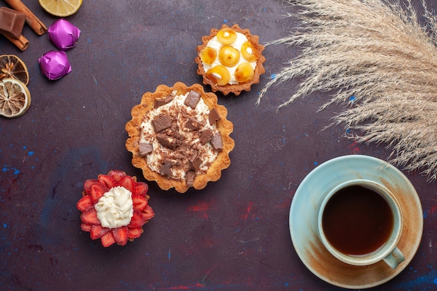 Draufsicht auf köstliche Kuchen zusammen mit Zimttee und Süßigkeiten auf der dunklen Oberfläche