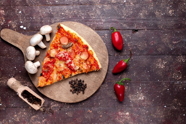 Draufsicht auf köstliche Pizzastück mit frischen Pilzen Tomaten Paprika auf braunem Schreibtisch