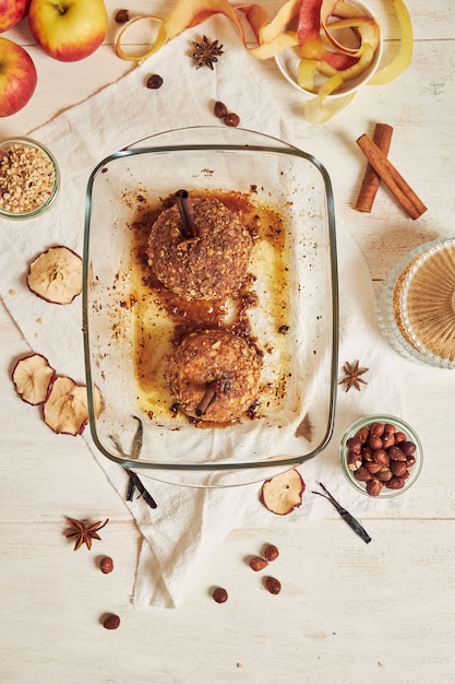 Draufsicht auf köstlichen Bratapfel mit Nüssen und Zimt für Weihnachten auf einem weißen Tisch