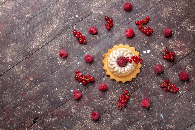 Draufsicht auf köstlichen kleinen kuchen mit zuckerpulver zusammen mit himbeeren-preiselbeeren entlang des braunen beerenfruchtkuchen-kekses