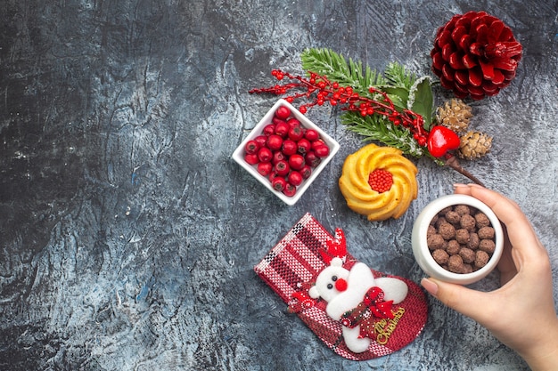 Draufsicht auf köstliches Keksdekorationszubehör Weihnachtsmannsocke und Cornell in einer Schüssel Tannenzweige auf der linken Seite auf dunkler Oberfläche