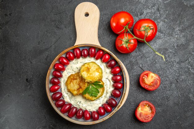 Draufsicht auf köstliches Kürbismehl mit frischen roten Hartriegeln und Tomaten auf grauer Oberfläche