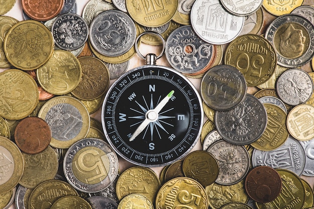 Draufsicht auf Kompass mit vielen Münzen