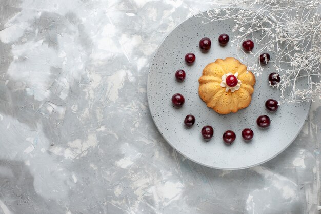 Draufsicht auf Kuchen mit Sahne und frischen Sauerkirschen auf hellem Schreibtisch, Kuchenplätzchenkeks süß