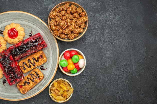 Draufsicht auf leckere fruchtige Kuchen mit Keksen und Bonbons im Dunkeln