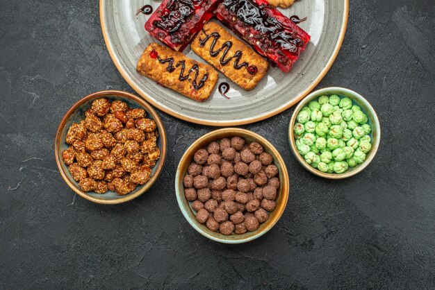 Draufsicht auf leckere fruchtige Kuchen mit Keksen und Bonbons im Dunkeln