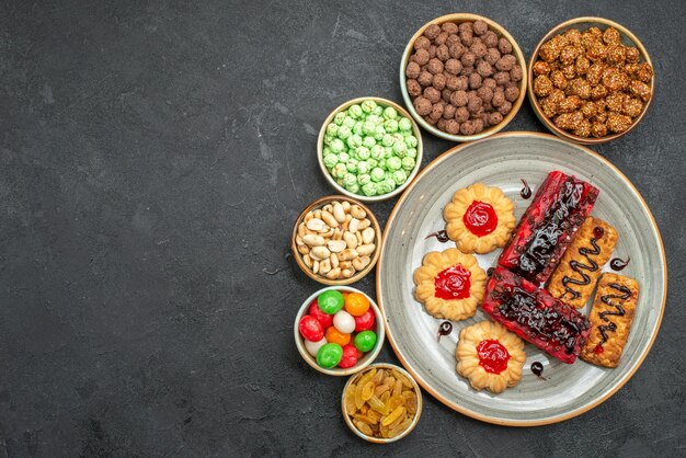 Draufsicht auf leckere fruchtige Kuchen mit Nüssen und Bonbons auf Grau